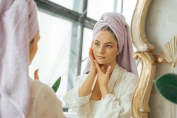 Mujer mirando al espejo haciendo una rutina de belleza