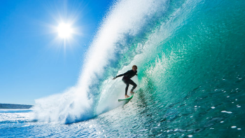 hombre surfea una increible ola en un mar cristalino
