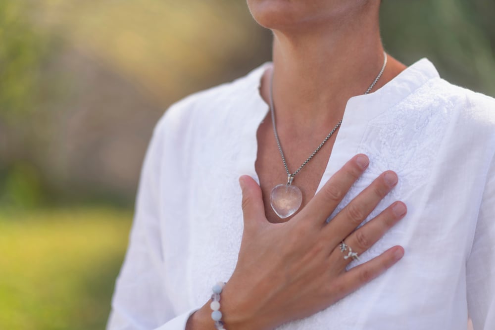 mujer de blanco con una mano en el corazon