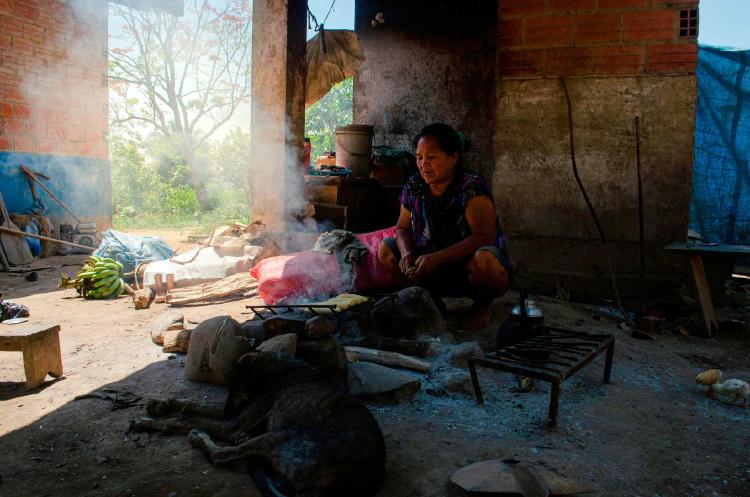 Una mujer Esse Ejja prepara la comida con leña y una pequeña parrilla.