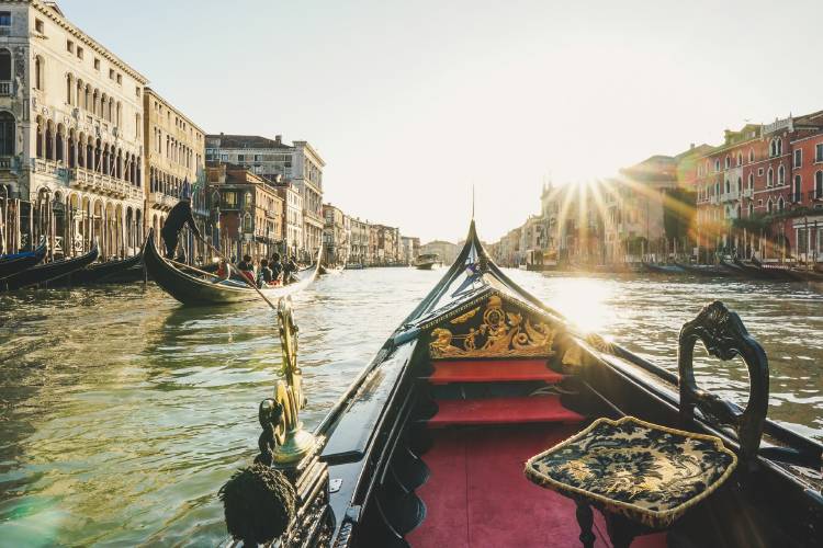 góndola en canal de Venecia con rayos de sol reflejándose en el agua