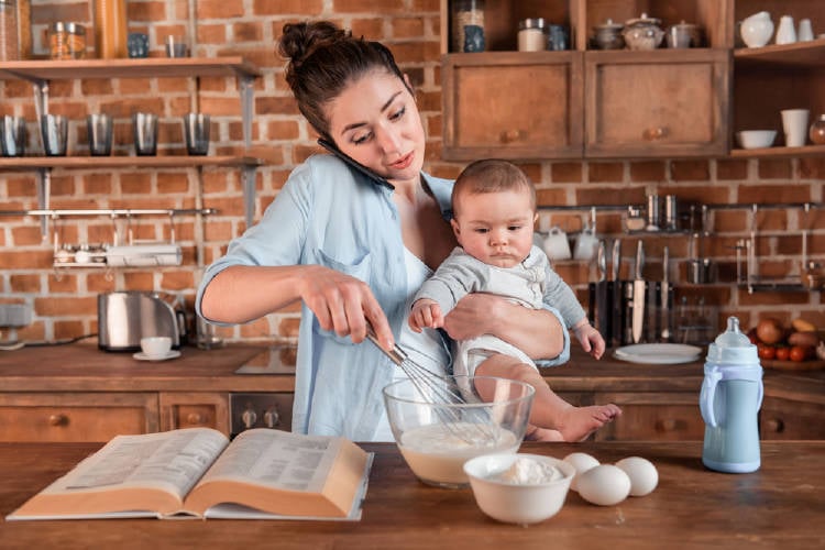 Una madre cocina con un bebé en brazos