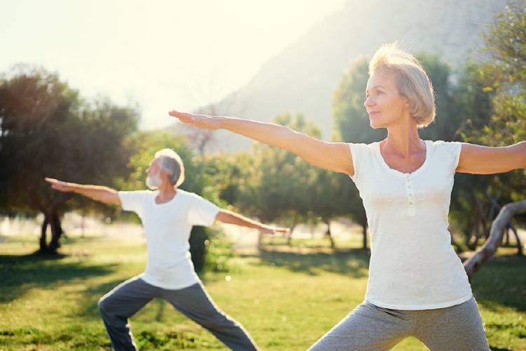 hombre y mujer de mediana edad practican yoga en parque