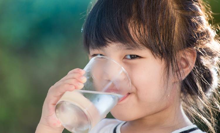 Una niña bebe un vaso de agua