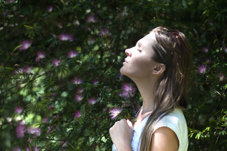 Una mujer de cara al sol con plantas de fondo