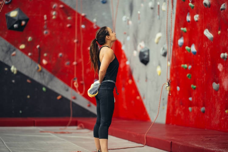 mujer escalando pared artificial