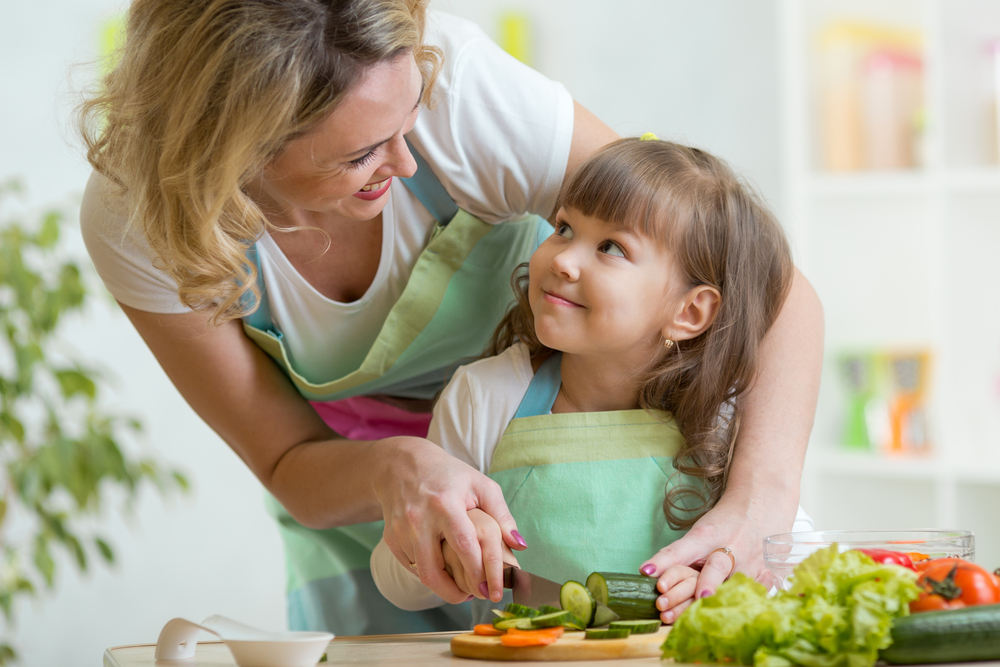 comida saludable mamá cortando verdura hija