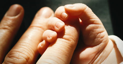 bebe recien nacido agarrando el dedo de su padre. concepto de vinculos de familia.