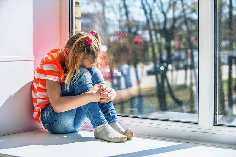 niña ansiosa frente a la ventana