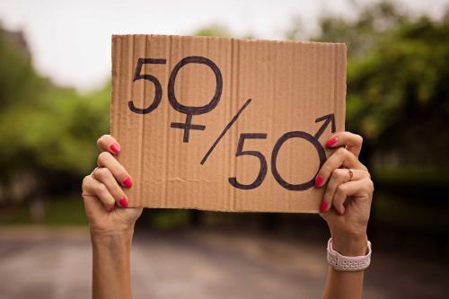 Manos de mujer alzando un cartel de cartón con mensaje de 50 y 50