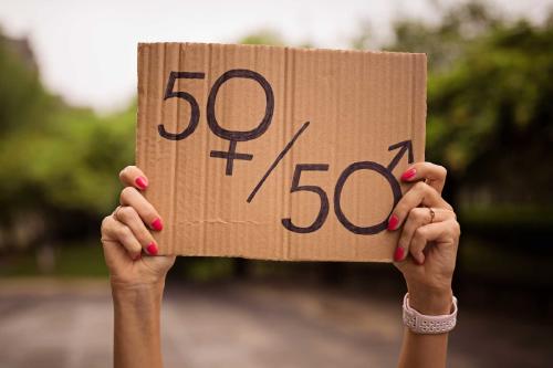 Igualdad de género asociada al desarrollo sostenible Manos de mujer alzando un cartel de cartón con mensaje de 50 y 50