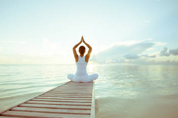 mujer practica yoga frente al mar