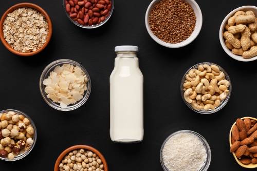 Una botella de leche con cereales y legumbres alrededor