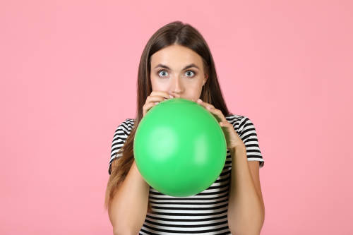 globos mujer infla un globo verde con su boca