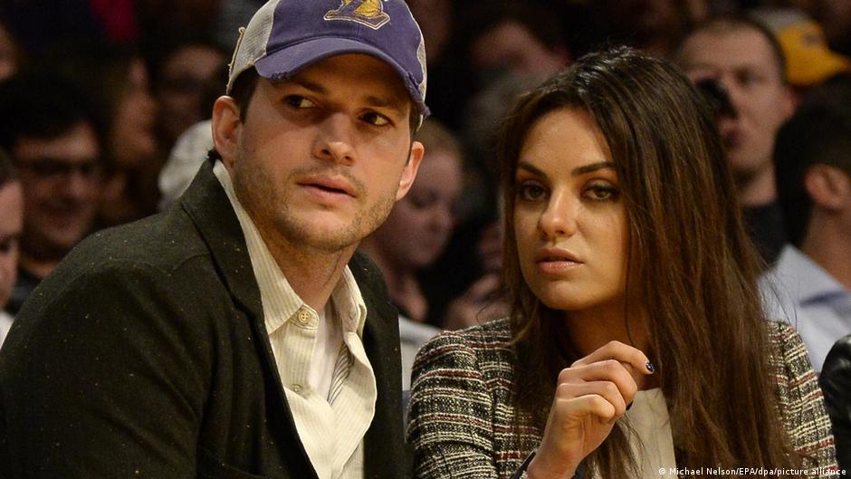 Ashton Kutcher y Mila Kunis como espectadores en un partido de baloncesto.