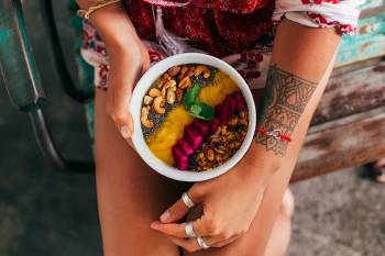 Una mujer con un bowl con frutas y frutos secos