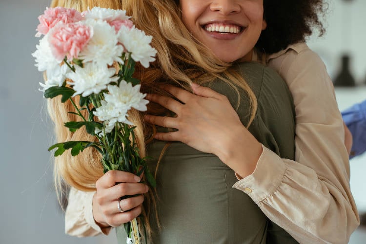 Una mujer le regala flores a otra