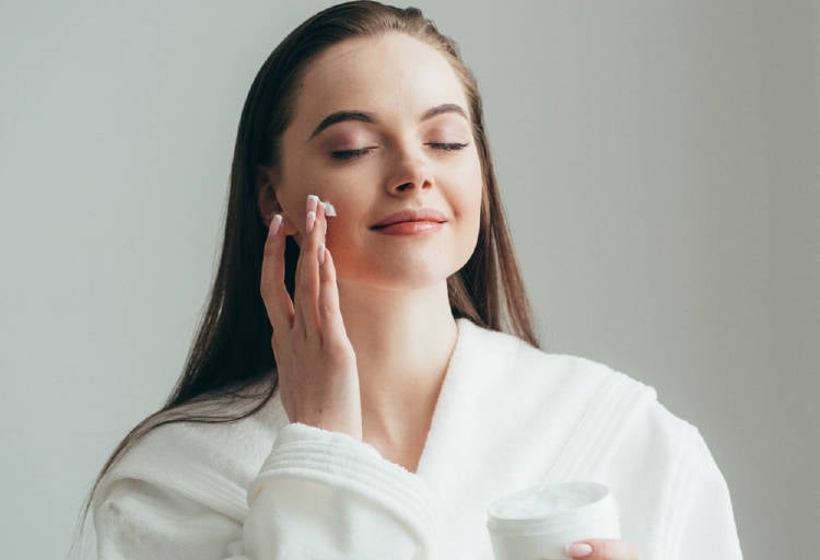 cuidado piel Una mujer se pone crema en el rostro
