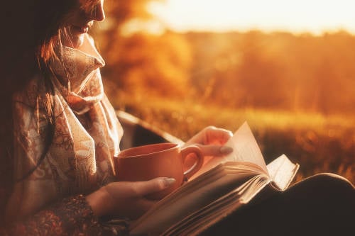 mujer disfruta de un libro y un cafe en soledad al aire libre