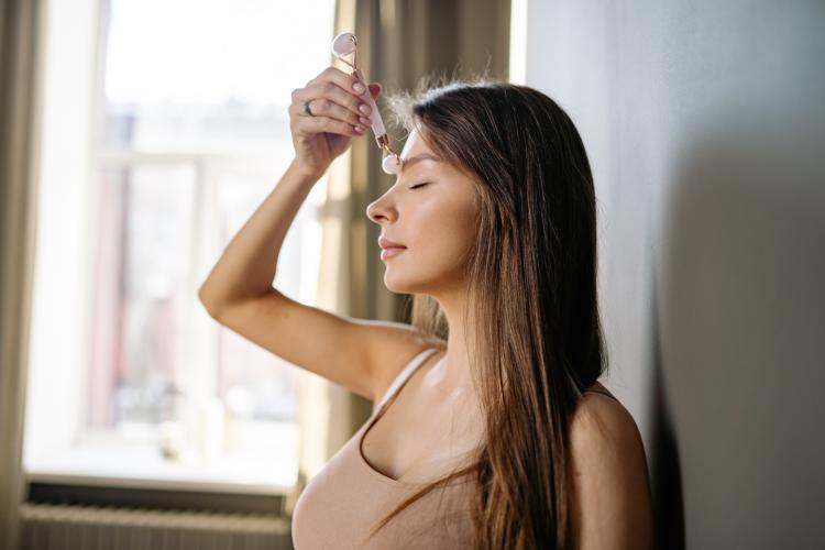 Foto de Yan Krukov en Pexels Mujer pasando un rodillo para automasaje por el rostro