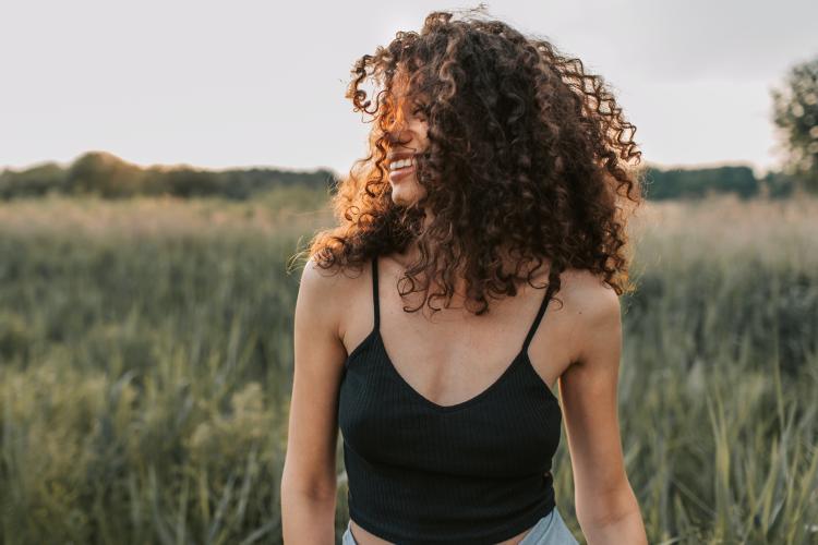 Mujer sonriente con cabello rizado en la naturaleza