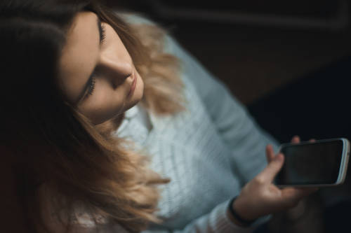 Una joven triste con el celular en la mano