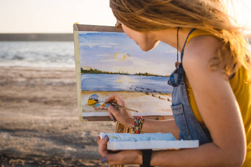 joven pinta un cuadro en la playa
