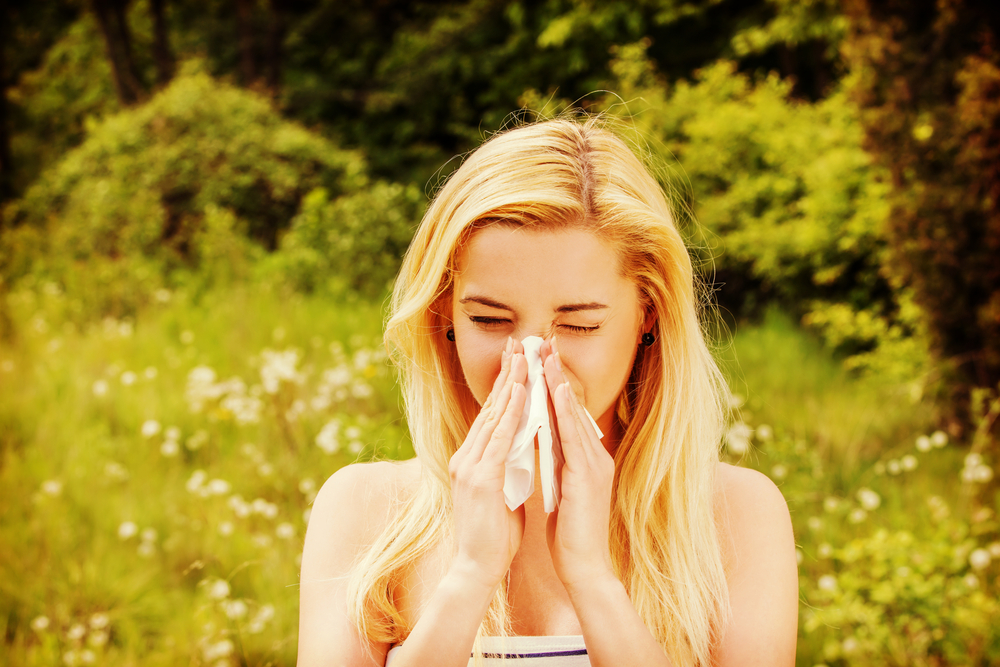 Una mujer con alergia se suena la nariz