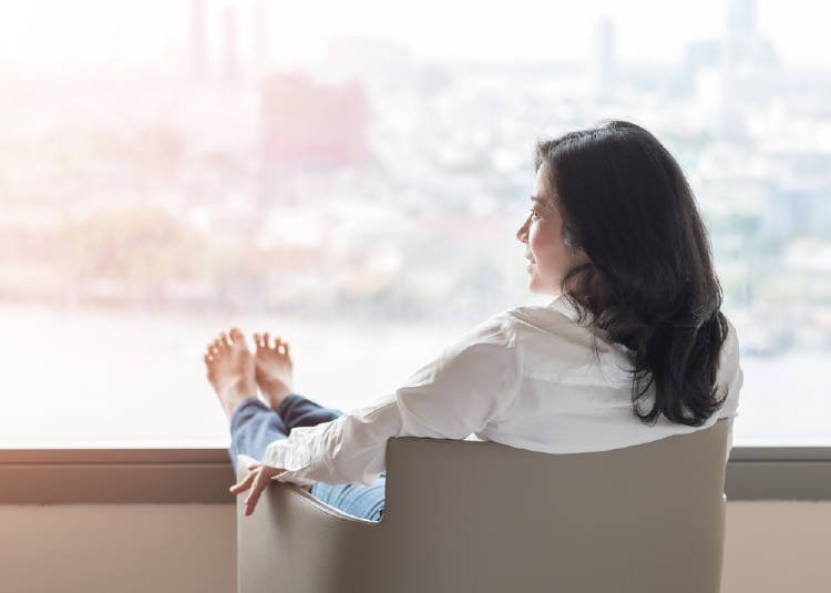 mujer descalza mirando por la ventana