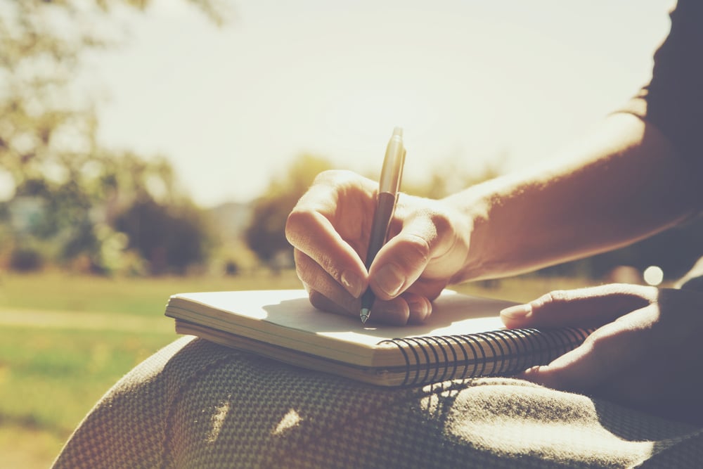 Una persona escribe en un cuaderno en un parque