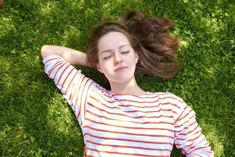mujer cesped Una mujer recostada sobre el césped con los ojos cerrados
