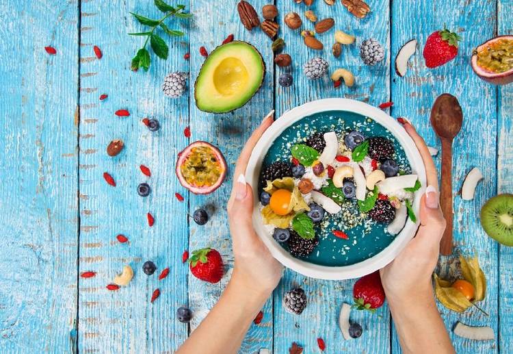 Una persona toma un recipiente lleno de frutas y verduras saludables