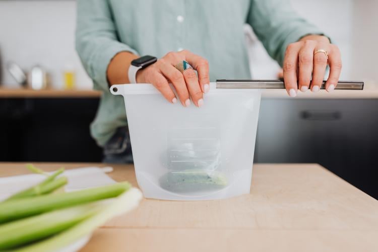 Persona colocando alimentos en una bolsa reutilizable de silicona