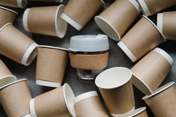 Vasos de café descartables rodeando un vaso reutilizable