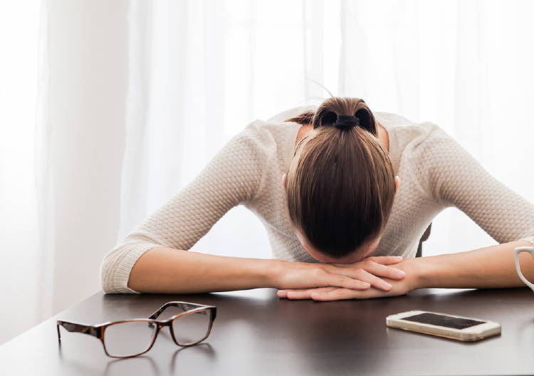 Una mujer estresada con la cabeza apoyada sobre la mesa