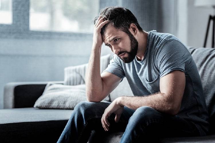 Un hombre triste sentado en un sillón