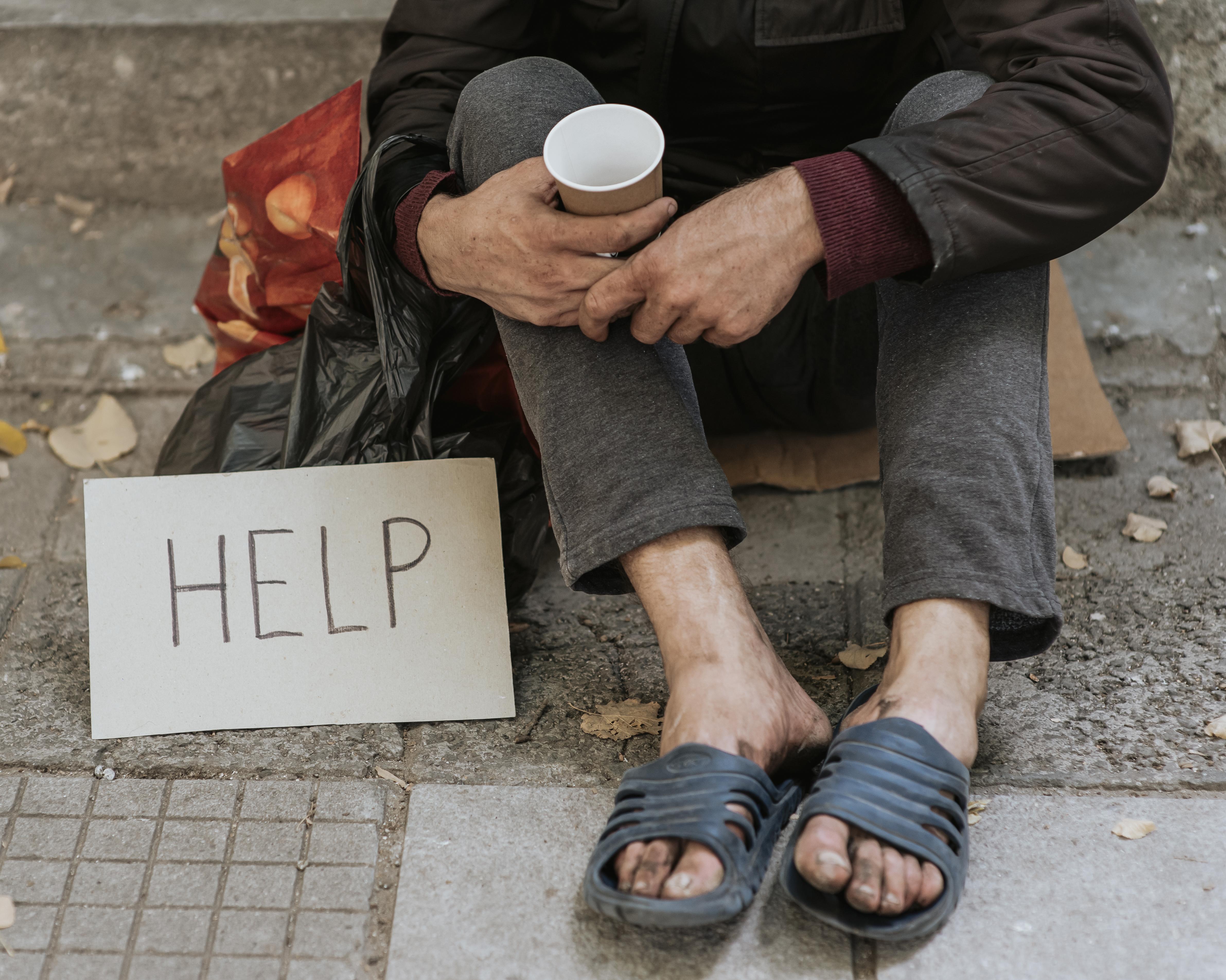 front view of homeless man outdoors with help sign and cup front view of homeless man outdoors with help sign and cup