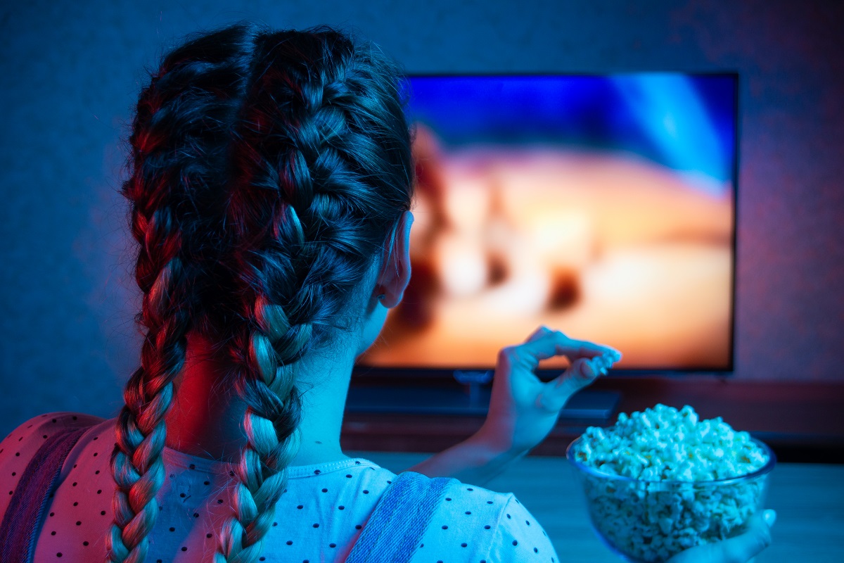 Una niña come pochoclo frente a la tele