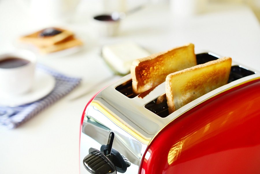 Un tostador con tostadas listas en una mesa con café