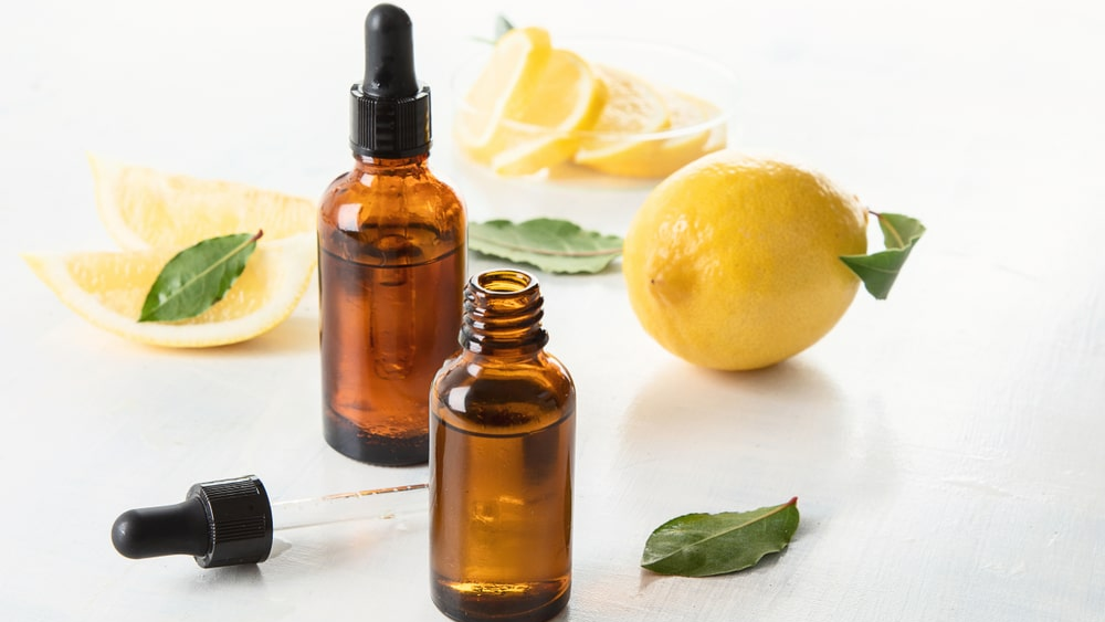 Ambientadores para el hogar, cómo hacerlos paso a paso-min Extracto de almendra en gotero abierto, y cerrado, limón entero, limón en trozos y hojas de menta