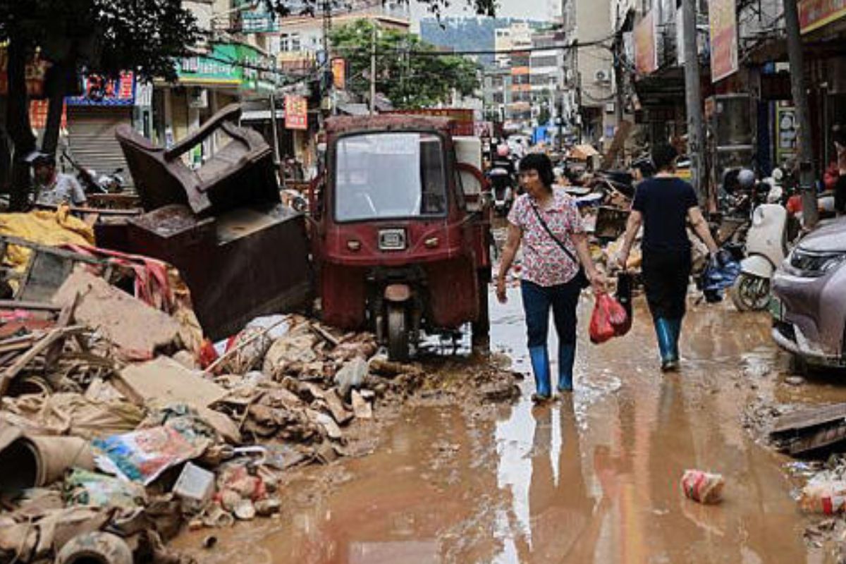 En esta foto difundida por la agencia de noticias Xinhua, varios residentes vadean entre los escombros de una calle afectada por las inundaciones en el condado de Huaiji, en la provincia meridional china de Guangdong, el 19 de junio de 2025.© Deng Hua/Xinhua via AP Photo 