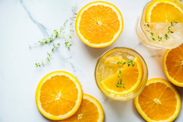 Naranjas cortadas al medio y dentro de un vaso