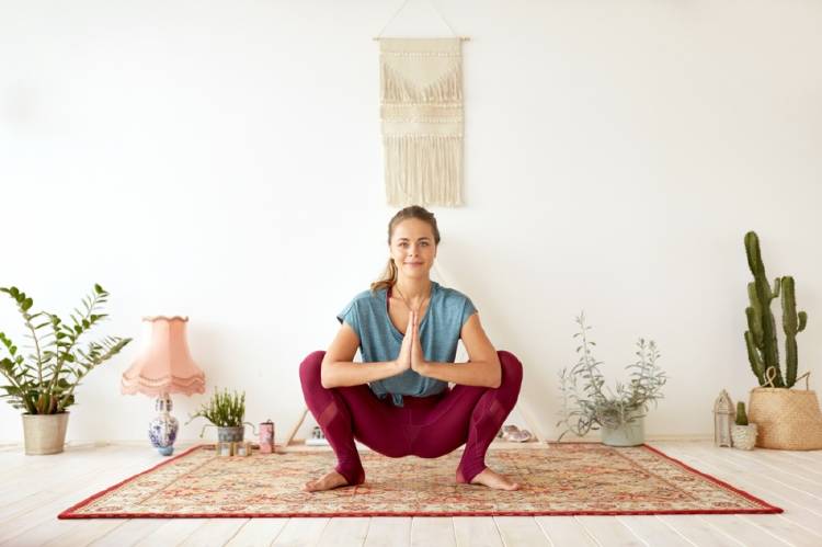 Una mujer practicando yoga en la postura Malasana