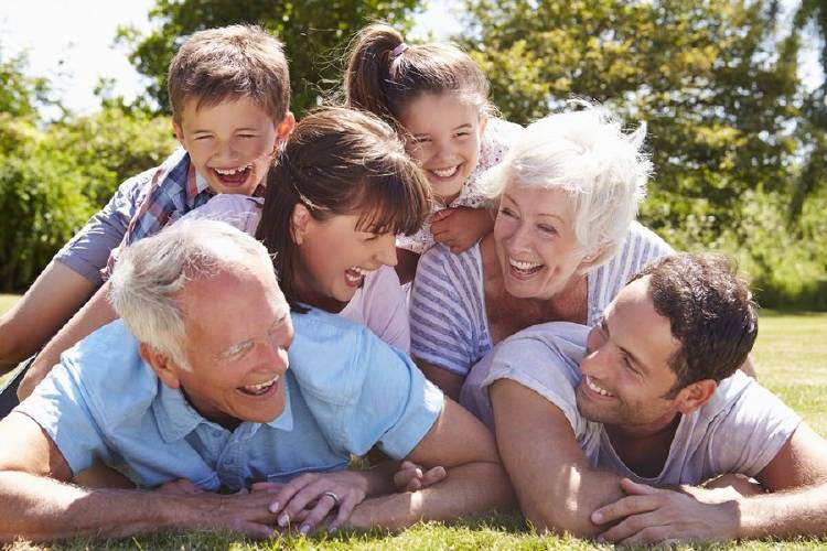 familia abuelos padres hijos Familia riendo en el césped