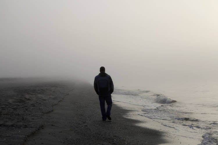 hombre camina en playa con niebla hombre camina en playa con niebla