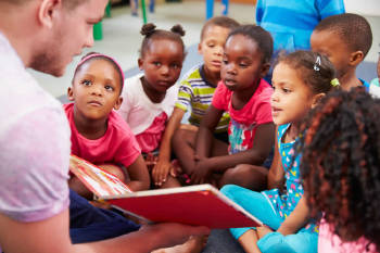 hombre voluntario enseña a leer a niños que viven en comunidades desfavorecidas