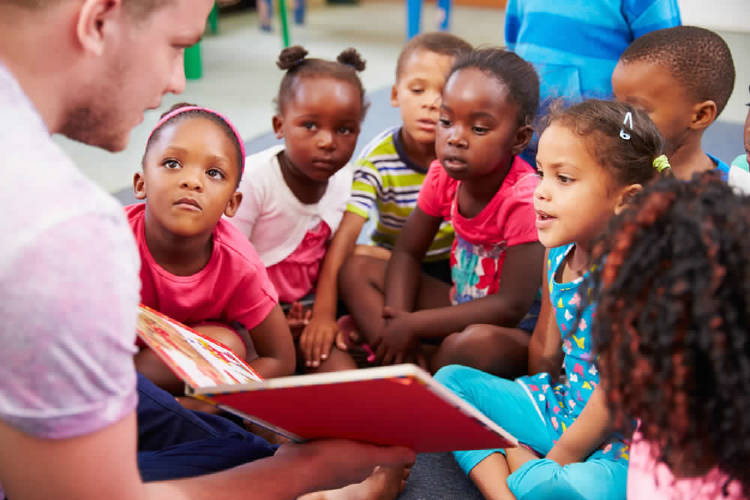 hombre voluntario enseña a leer a niños que viven en comunidades desfavorecidas