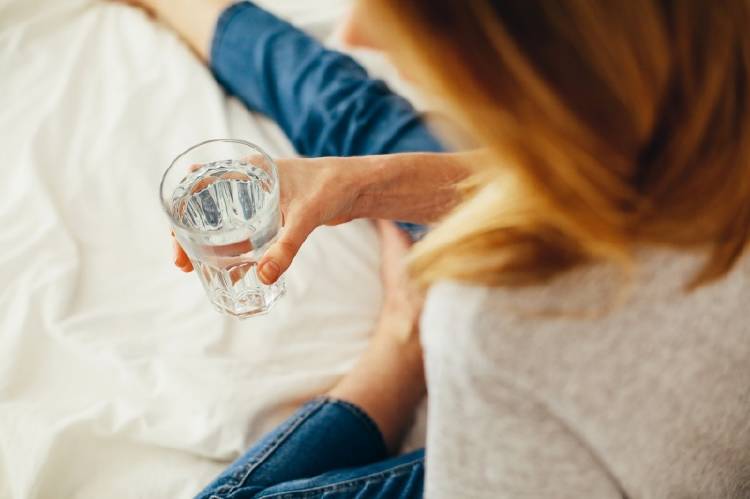 Una mujer bebe agua en la cama