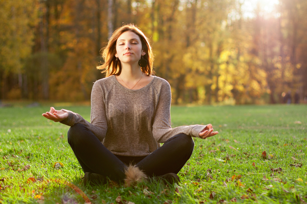 mujer medita en postura de loto en la naturaleza