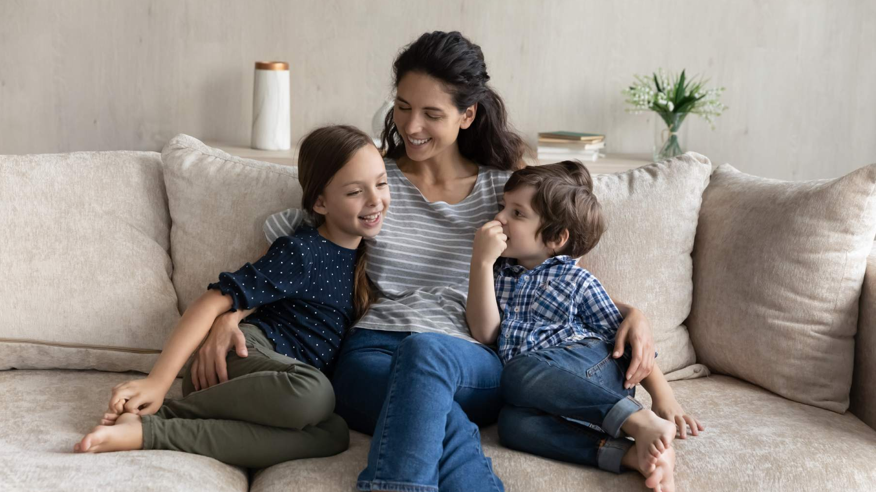 Madre abrazando a dos hijos sentados en el sillón